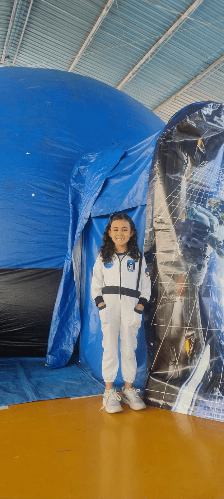 Menina com roupa de astronauta em evento educativo